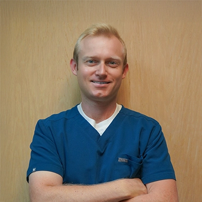 Noel Berry smiles while wearing blue scrubs.